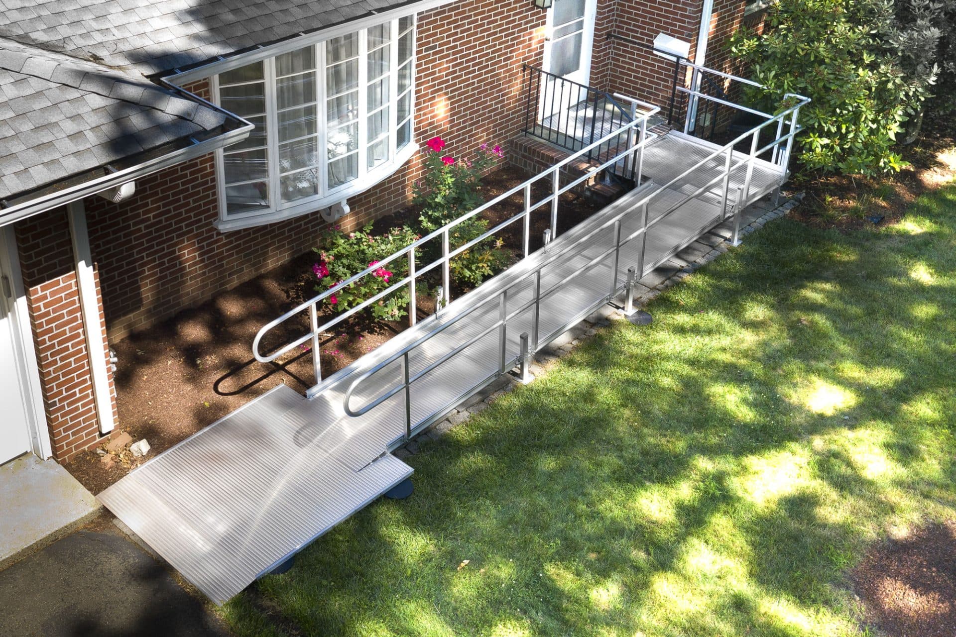 Aerial view of an L-shaped modular aluminum ramp fitted along the front of a brick home