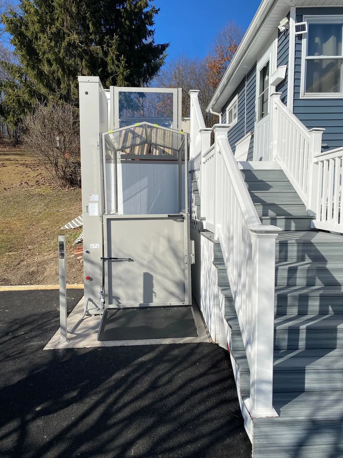 Vertical platform lift installed beside the porch steps of a home