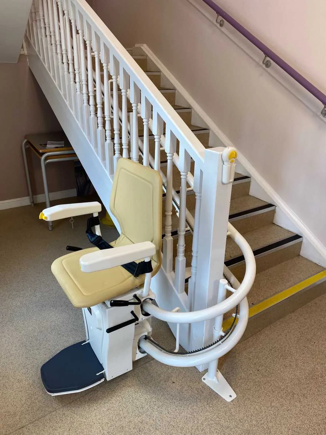 Curved stairlift with its rail wrapping the bottom of a turning staircase