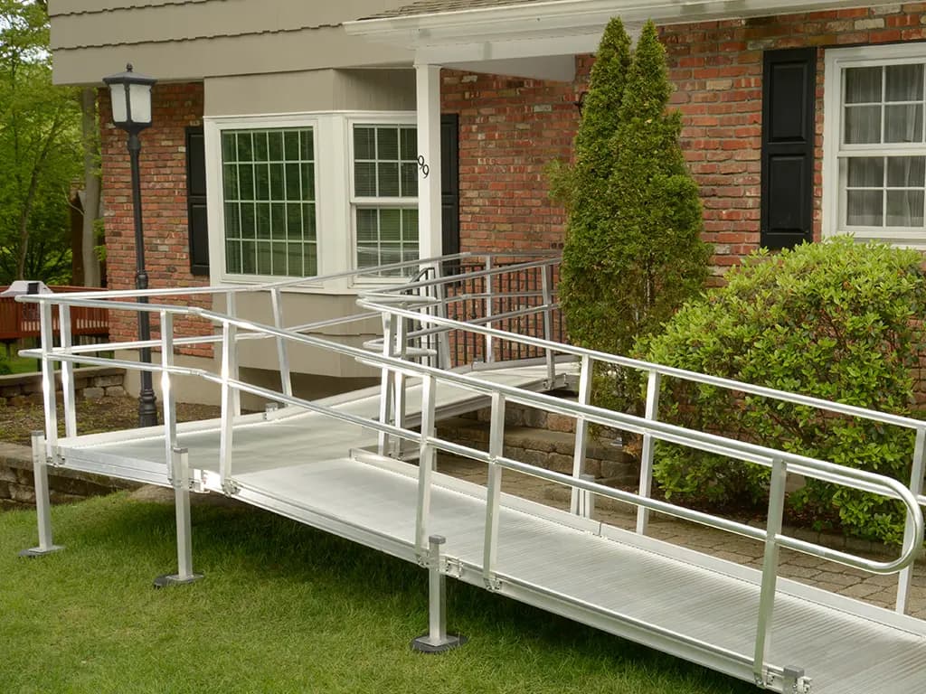 Modular aluminum ramp with handrails installed at the front entrance of a brick home